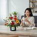 Well Live Florist Flower Pop arrangement with white lilies, orange and yellow gerberas, pink and red carnations, and purple statice in a black box.