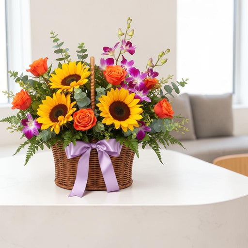 Sunflower Tango Basket featuring fresh sunflowers, orange roses, purple orchids, and green foliage in a woven basket arrangement.