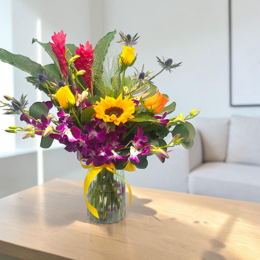Tropicana Sunrise fresh flower vase arrangement with red ginger torch, sunflowers and purple orchids on wooden table