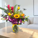 Tropicana Sunrise fresh flower vase arrangement with red ginger torch, sunflowers and purple orchids on wooden table