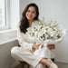 Woman holding Pure Serenity all-white fresh flower bouquet with satin ribbon