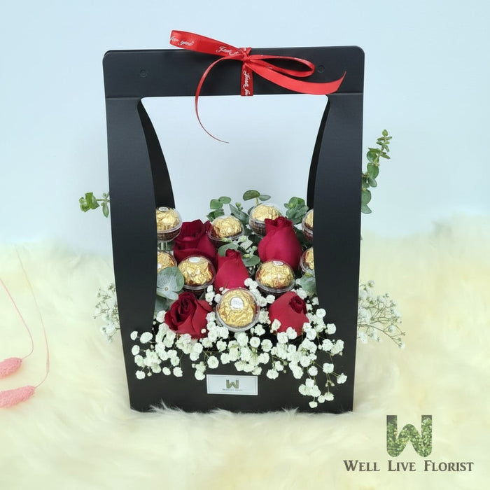 Well Live Florist Finley flower box with red roses, baby's breath, and Ferrero Rocher chocolates in a black carrier.