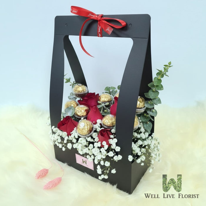 Well Live Florist Finley flower box with red roses, baby's breath, and Ferrero Rocher chocolates in a black carrier.