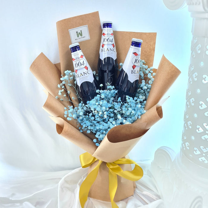 A hand bouquet featuring three bottles of beer placed amidst fresh blue baby's breath flowers, wrapped in brown paper with a yellow ribbon.