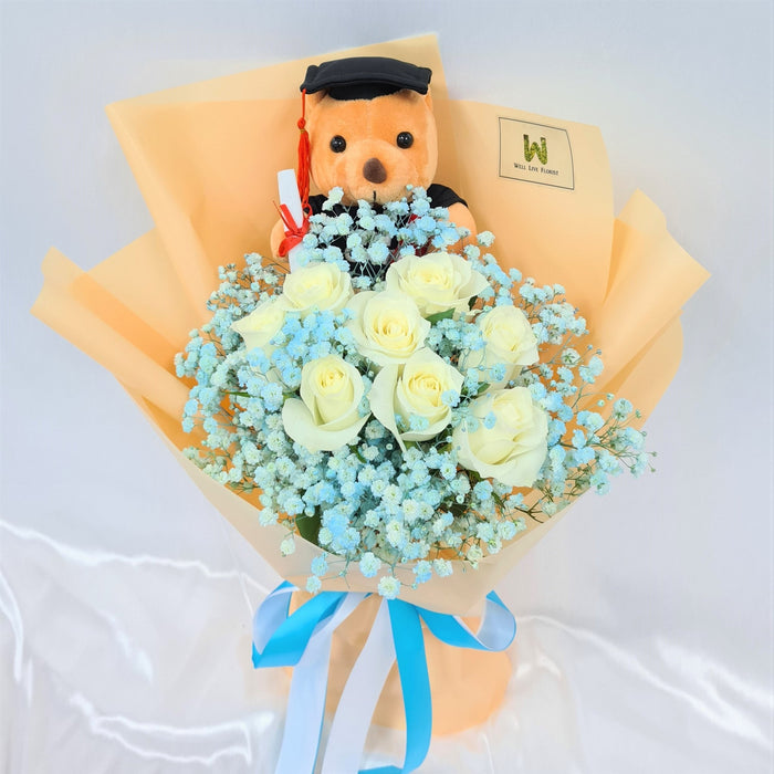 Charming hand bouquet of ravishing roses, baby's breath and a graduation bear.