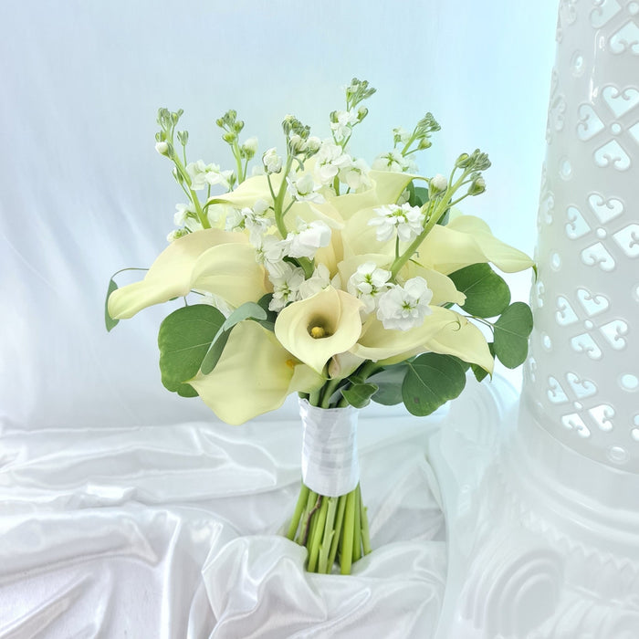 Graceful hand bouquet of beautiful white calla lily, matthiola and Foliage