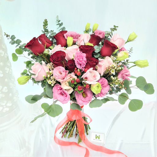 Exquisite hand bouquet of enticing pink / red roses, wax flower, eustoma and foliage