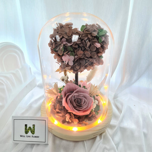 Captivating combination of preserved cappuccino roses, hydrangeas, and dried foliage in glass dome to celebrate the day.