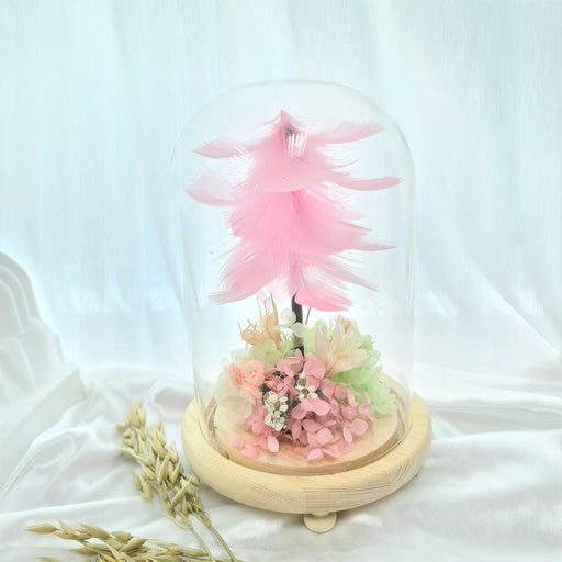 Captivating combination of pink feather, preserved hydrangeas and dried foliage in glass dome to celebrate the day.