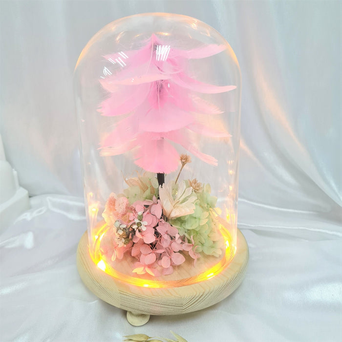 Captivating combination of pink feather, preserved hydrangeas and dried foliage in glass dome to celebrate the day.