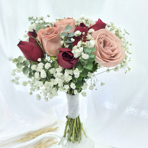 Exquisite hand bouquet of enticing red / cappuccino roses and baby's breath.