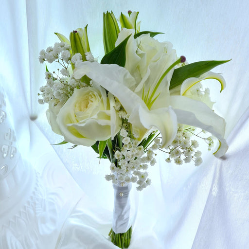 Charming hand bouquet of 10 enticing white roses and 3 beautiful white lilies.