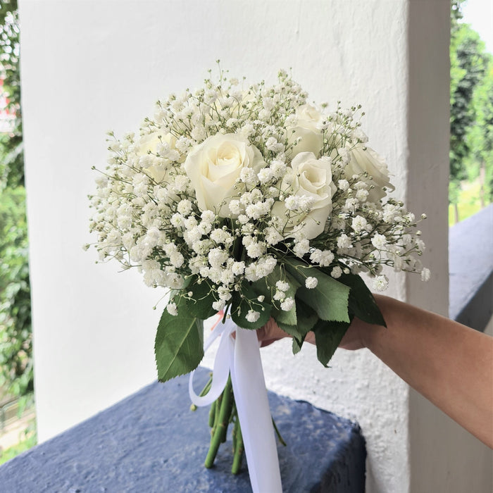 Exquisite bridal hand bouquet of enticing roses and baby's breath.