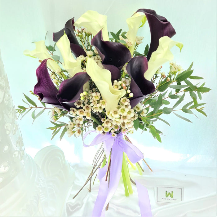 Graceful hand bouquet of beautiful 12 white / purple calla lily, wax flower and foliage