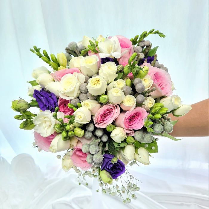 Graceful hand bouquet of pink roses, purple eustoma, filler and foliage