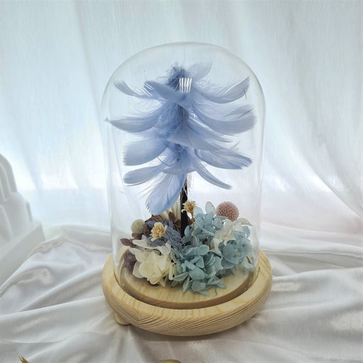 Captivating combination of light blue feather, preserved hydrangeas and dried foliage in glass dome to celebrate the day