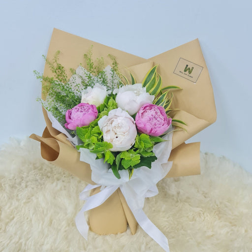 A beautiful seasonal display of fluffy pink and white Peonies and accompanied by delicate green Hydrangea.