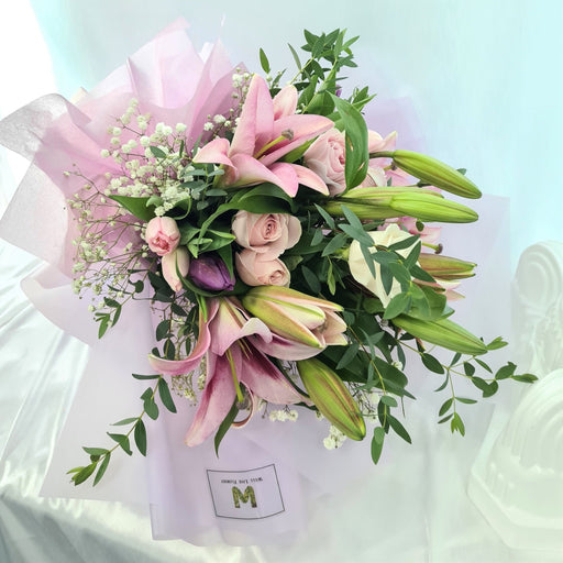 Ravishing hand bouquet of gorgeous pink lilies, roses, tulips, baby's breath and foliage