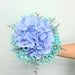 Exquisite hand bouquet of enticing blue hydrangea and baby's breath.