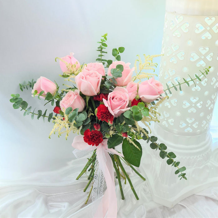 Captivating hand bouquet of irresistible roses, carnation, and foliage.